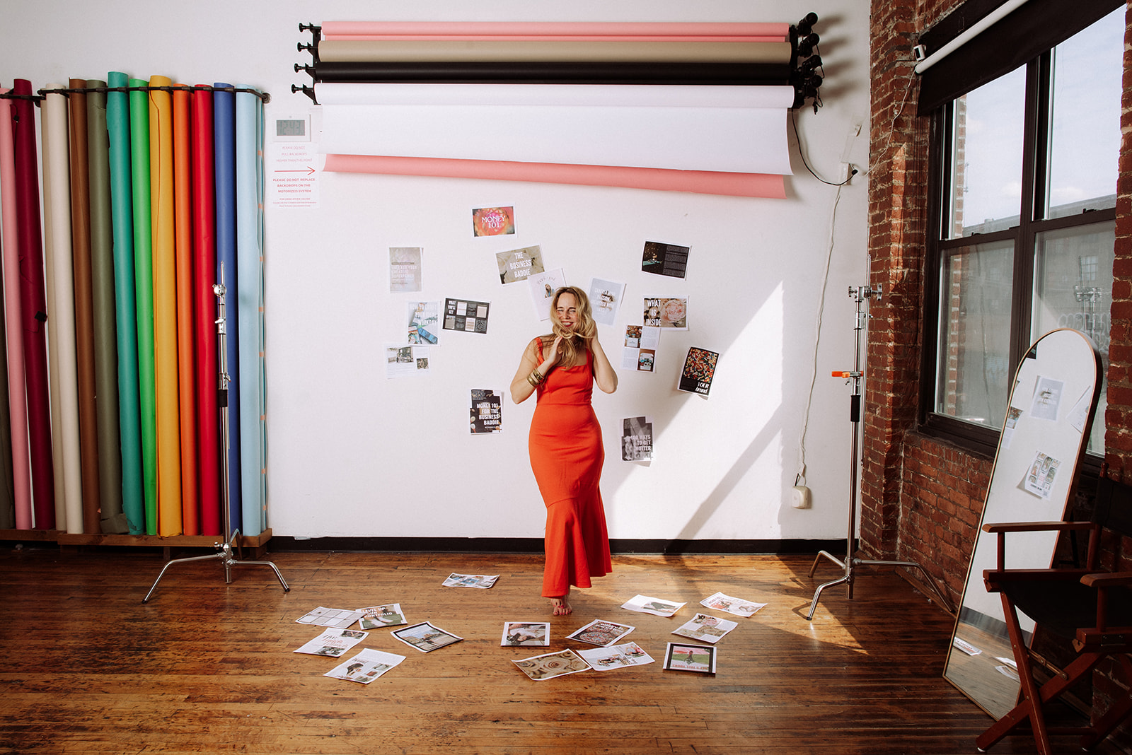 Creative entrepreneur standing barefoot in a bright studio with colorful backdrops and magazine pages scattered around, symbolizing vision and inspiration for scaling a creative business.