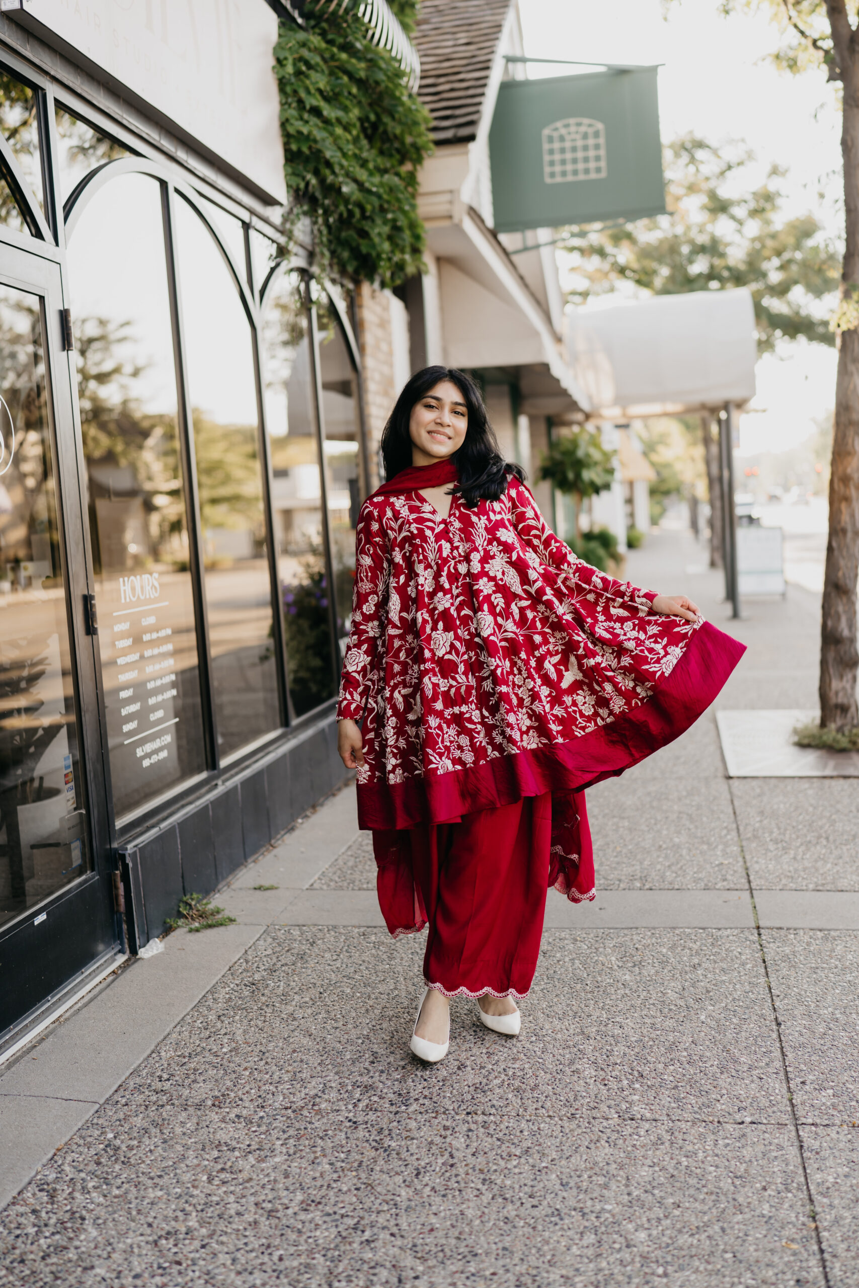 Minnetonka High School senior Mehreen walking confidently in Downtown Excelsior wearing a red embroidered outfit during her senior photo session.