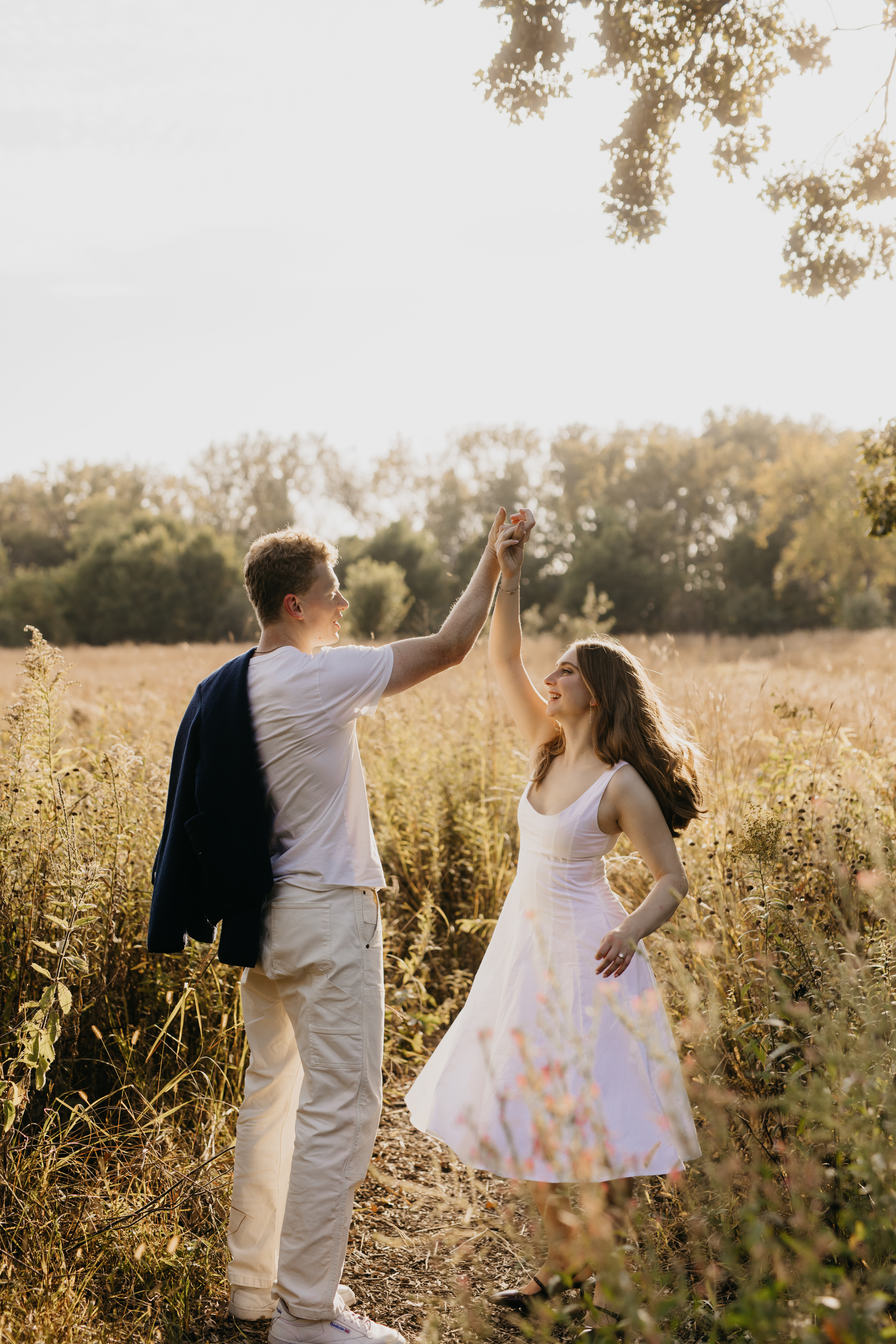 Couple dancing in a golden Minneapolis field during sunset engagement session captured by Mycah Bain Photography.