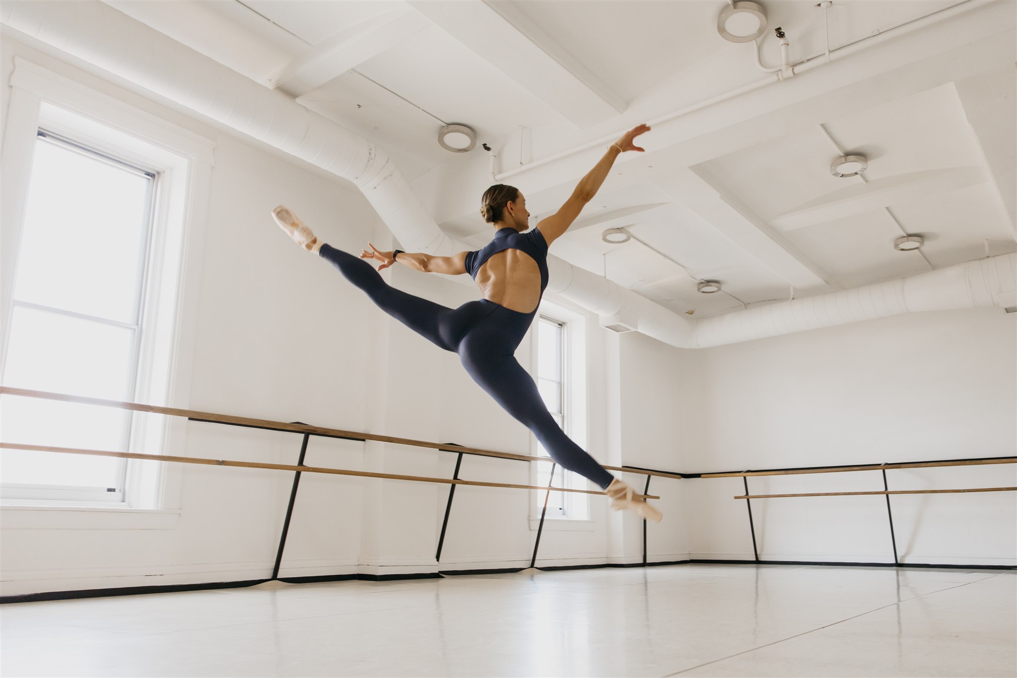 Dancer performing a grand jeté in a bright studio, photographed by dance photographer Minneapolis Mycah Bain.
