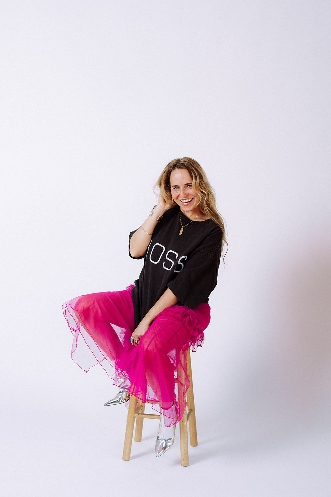 Entrepreneur wearing a bold black “BOSS” tee, bright pink tulle skirt, and silver boots during brand photos in Minneapolis.