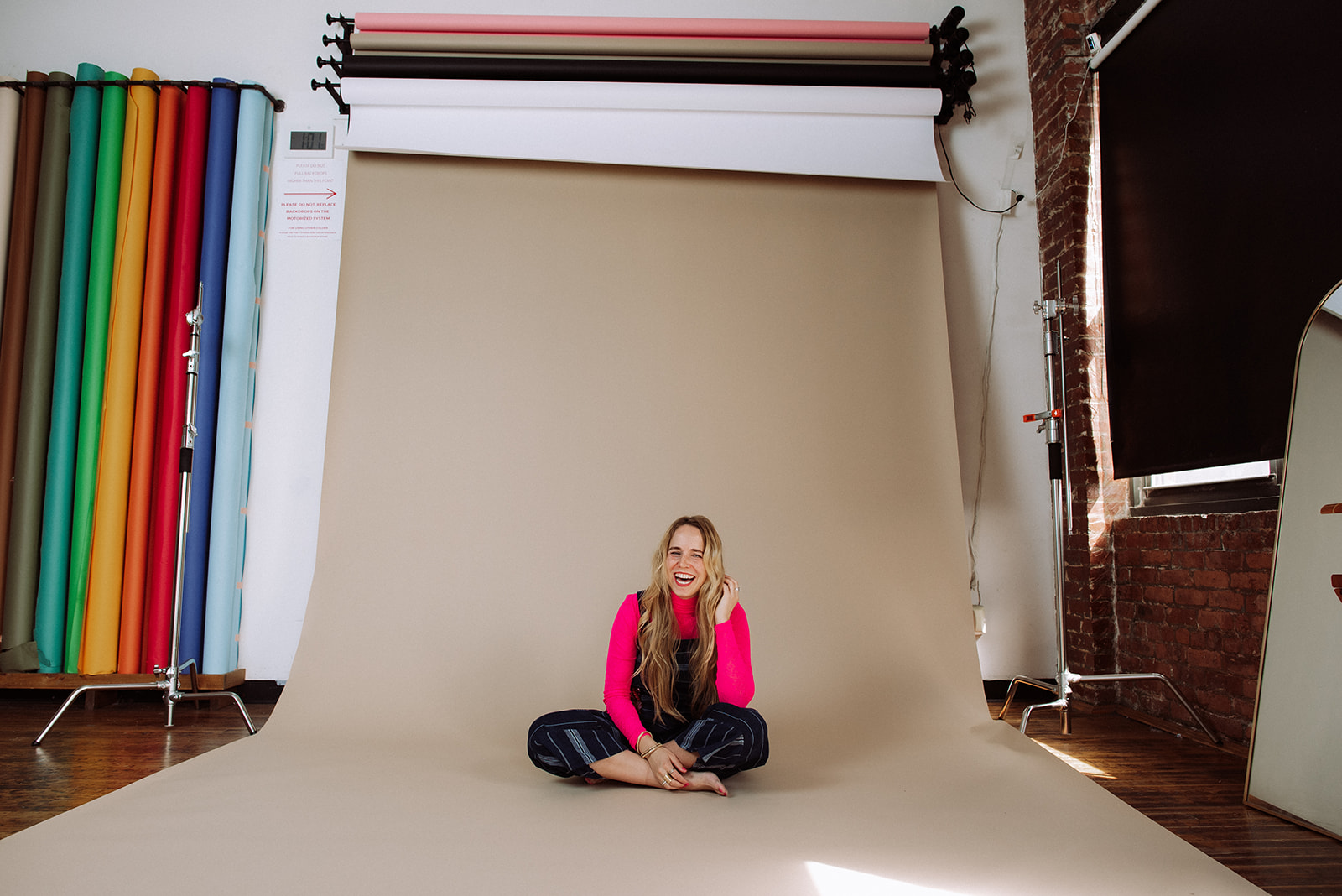A creative studio portrait of Mycah Bain sitting on a seamless backdrop, representing how to grow a multi-passionate business through photography and joyful creativity.
