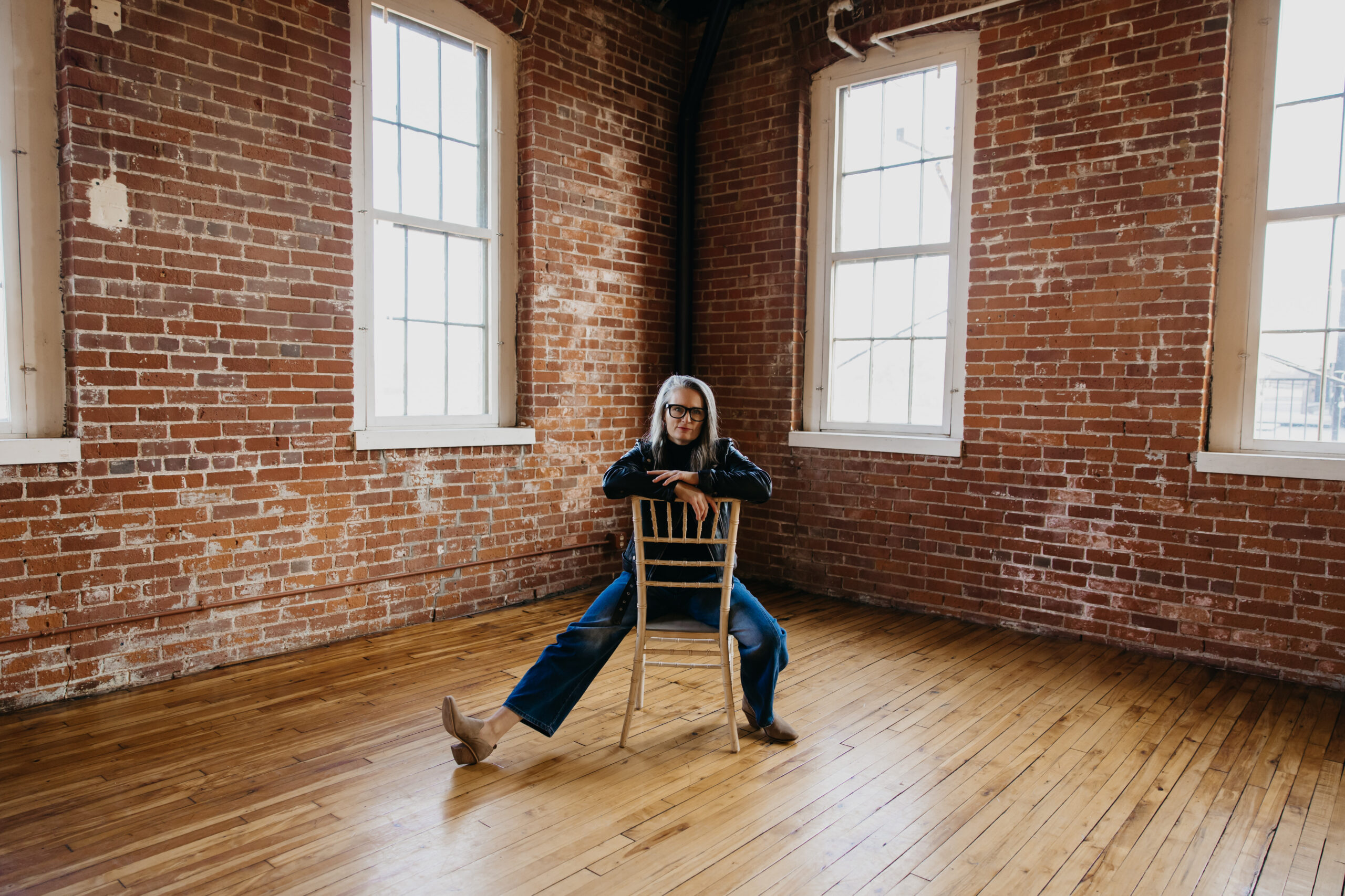 Sara Larson menopause coach and educator seated in an industrial studio during her brand photography session with Mycah Bain Photography in Minneapolis