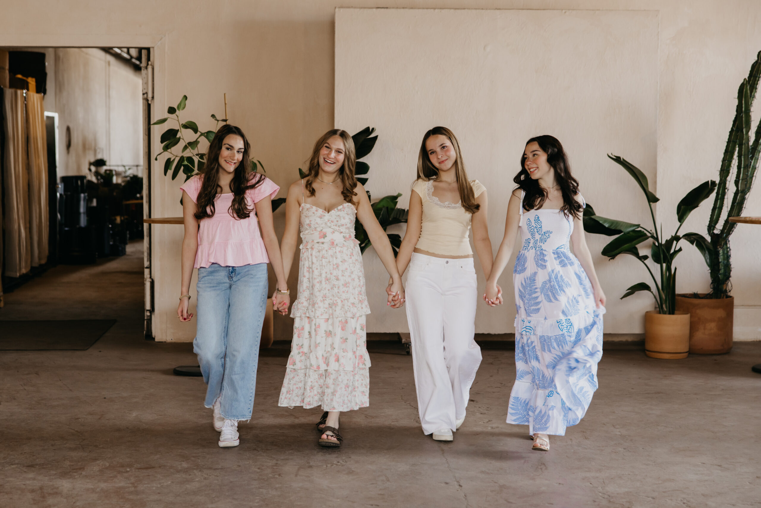 Four Minneapolis senior girls walking hand in hand at Mother Co. Plants, Minneapolis senior portrait session by Mycah Bain Photography