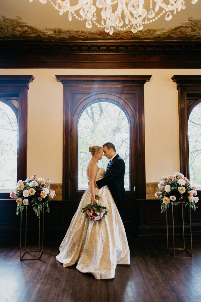 Bride and groom portrait in a grand historic room with chandelier and arched windows, elegant Minneapolis wedding photography