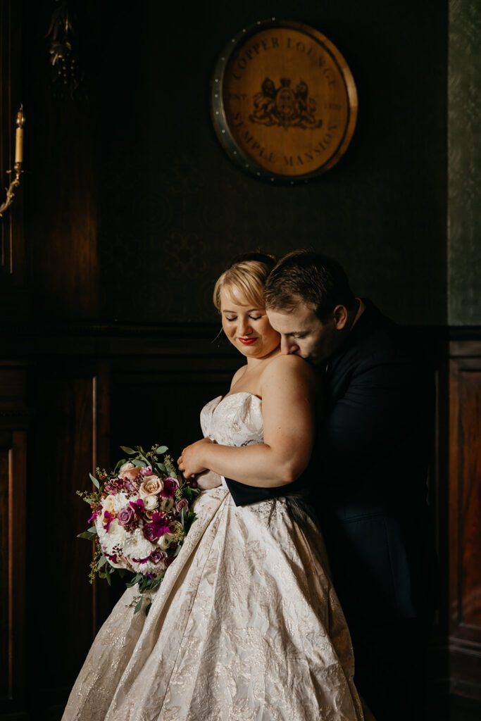 Bride and groom embracing in a moody dark wood interior, romantic Minneapolis wedding photography by Mycah Bain
