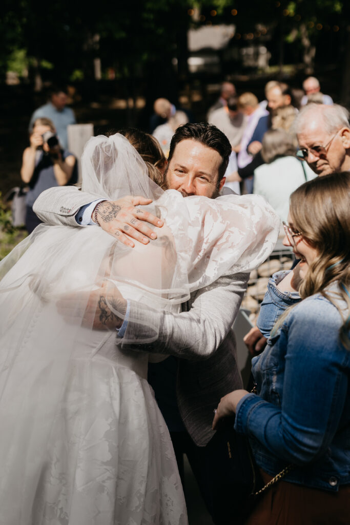 Groom hugging a family member during post-ceremony celebrations at a Minnesota outdoor wedding