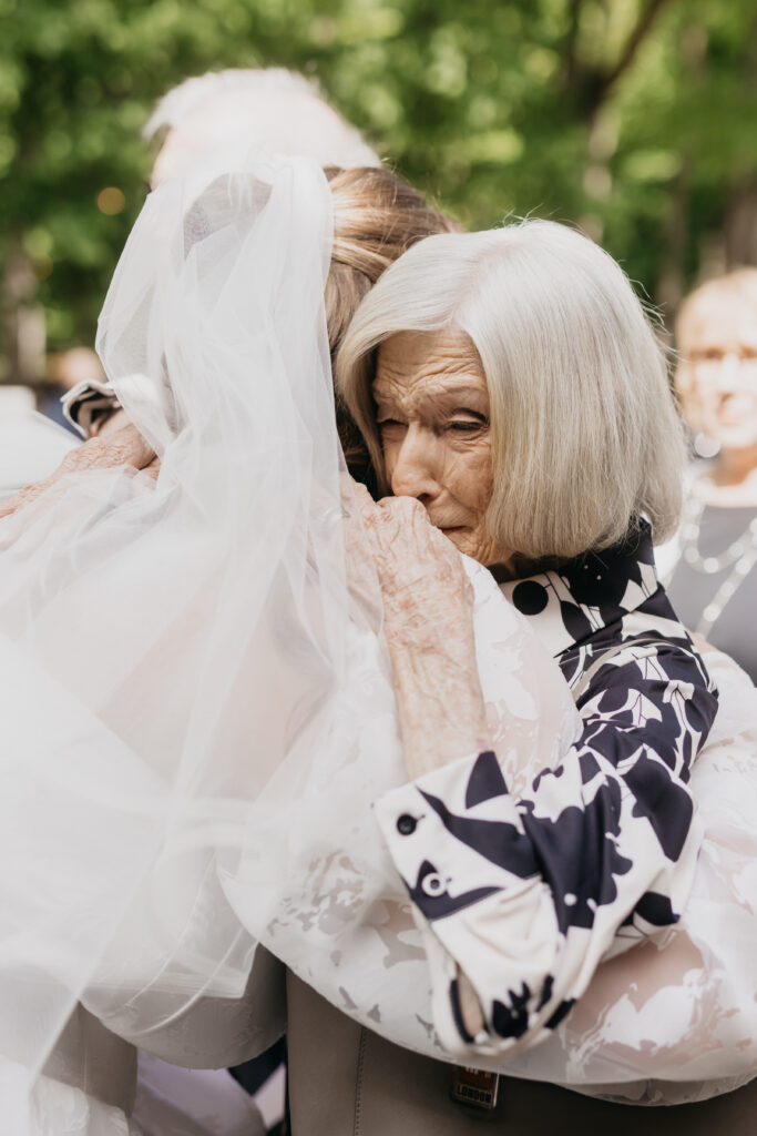 Grandmother overcome with emotion hugging bride after outdoor wedding ceremony, documentary wedding photography Minnesota