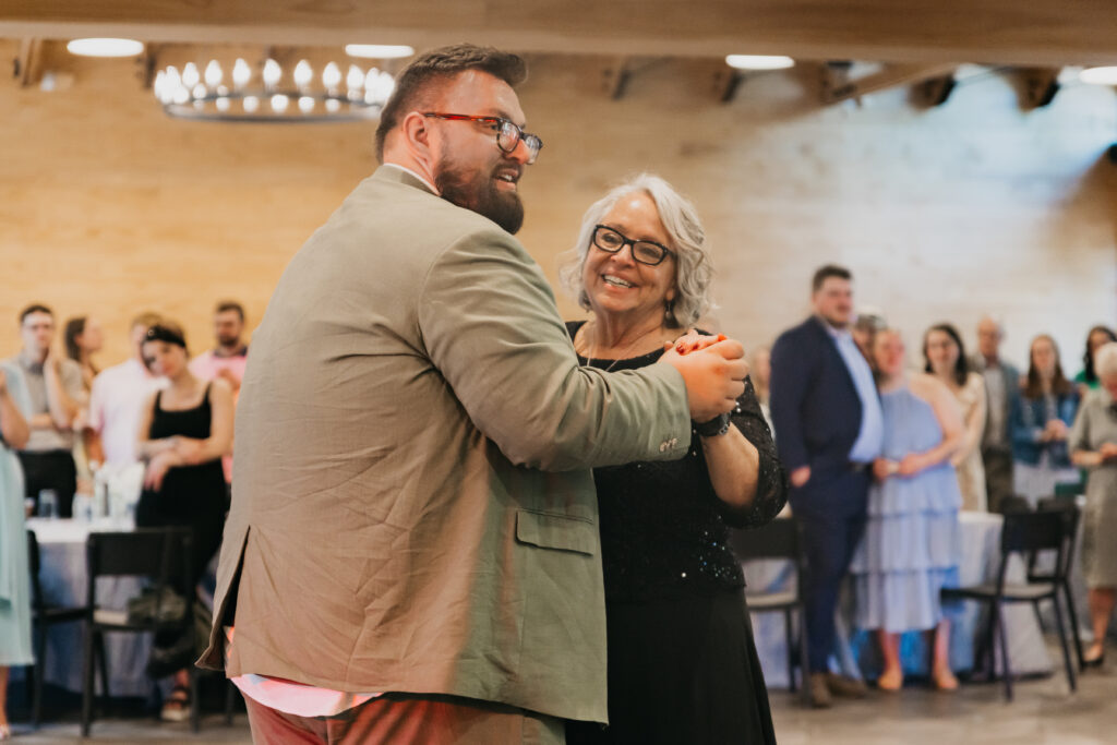 Groom dancing with his mother at wedding reception, candid parent dance photo by Mycah Bain Photography