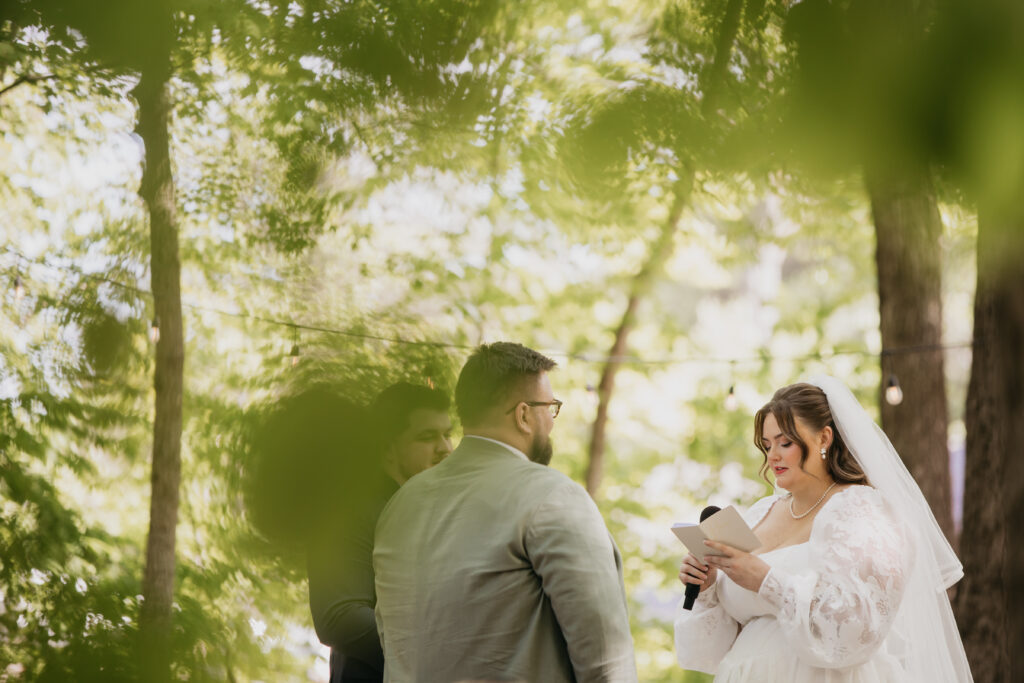 Bride reading vows during an outdoor forest ceremony, documentary wedding photography Minneapolis