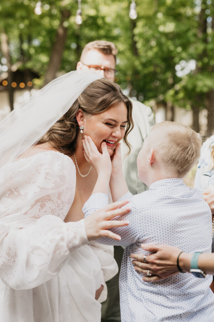 Bride laughing with a young child guest after the ceremony at an outdoor Minnesota wedding
