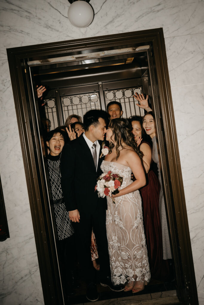 Wedding party crammed into an elevator laughing and celebrating, Minneapolis wedding photographer