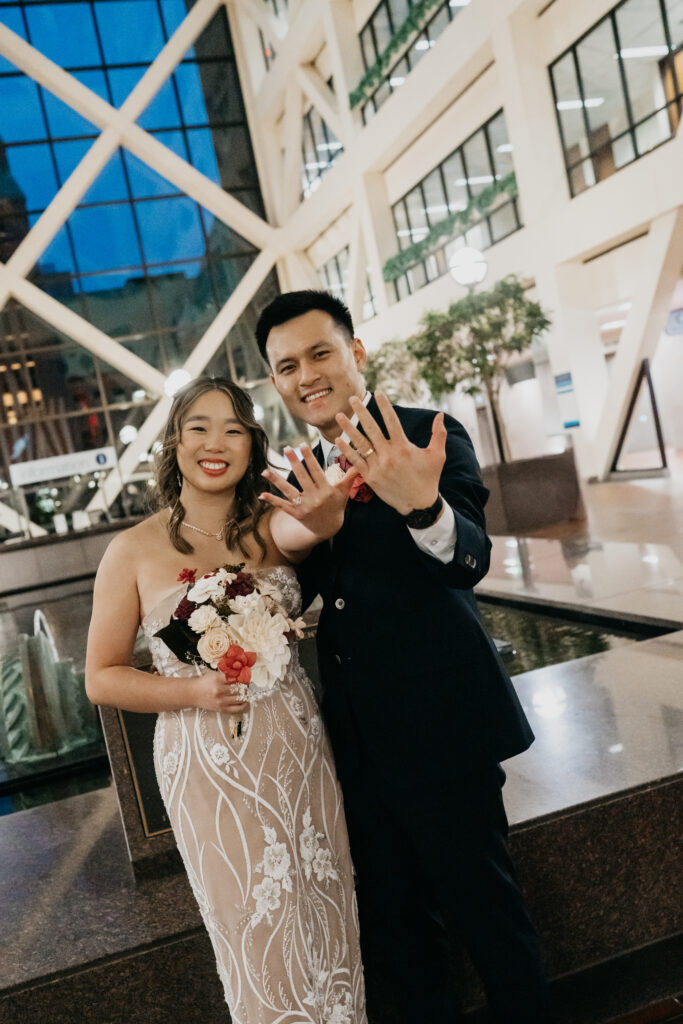 Bride and groom showing off wedding rings inside a modern Minneapolis venue after ceremony