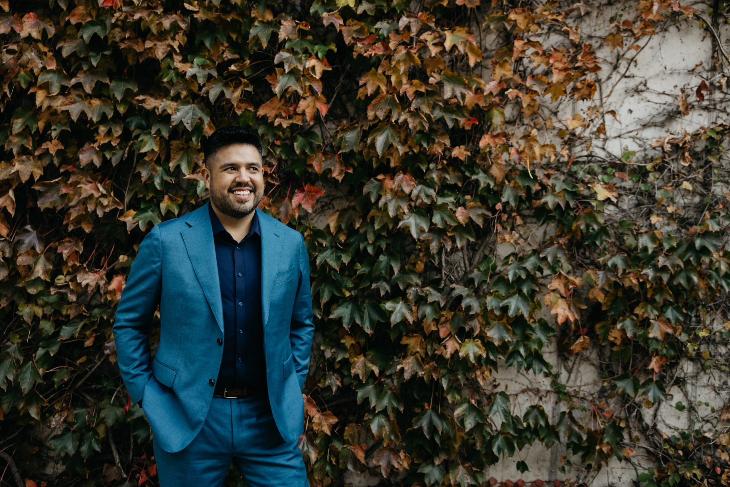 Professional brand photography Minneapolis — man in teal suit standing in front of ivy wall, confident lifestyle portrait by Mycah Bain Photography