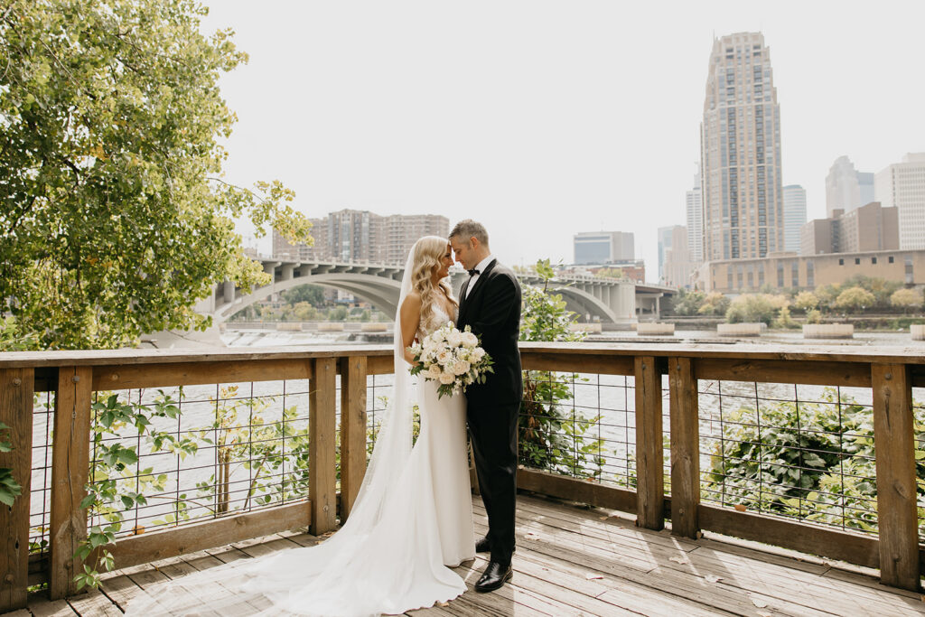 Bride and groom portraits along the Mississippi River with Stone Arch Bridge visible, Minneapolis wedding photographer