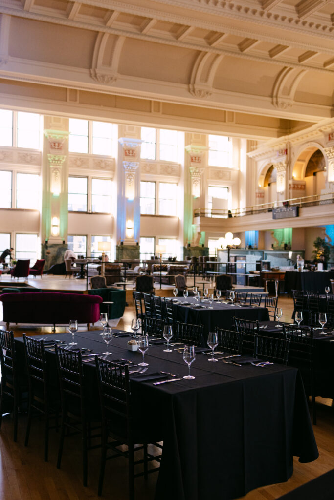 Minneapolis Grain Exchange historic trading floor set with black-draped dinner tables and crystal stemware for MPR corporate event — Mycah Bain Photography