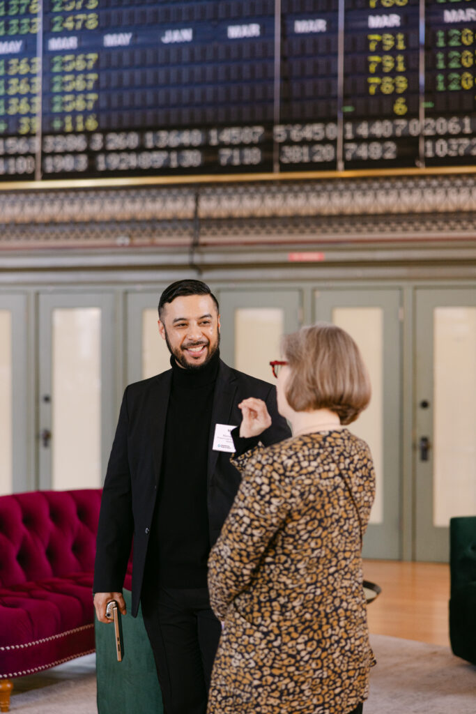 MPR corporate event guests networking in front of historic stock ticker board at the Minneapolis Grain Exchange — corporate event photography by Mycah Bain Photography