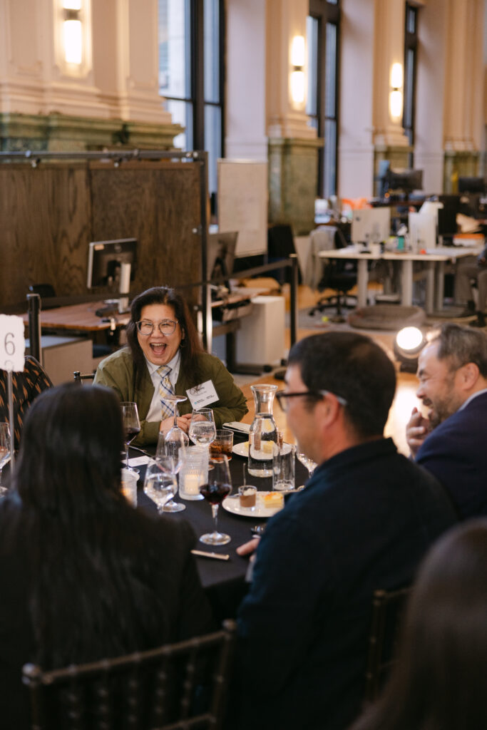 Minnesota Public Radio gala guest laughing during dinner program at the Minneapolis Grain Exchange — corporate event photography by Mycah Bain Photography