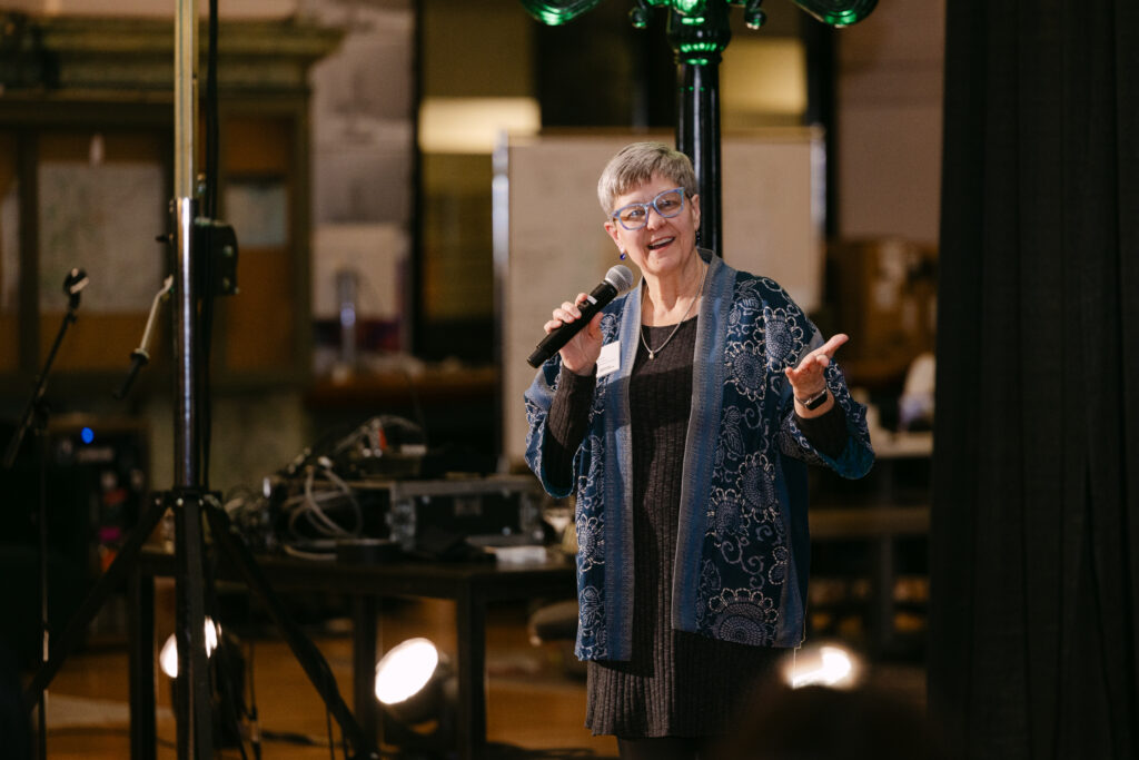 Minnesota Public Radio speaker presenting with handheld microphone on stage at the Minneapolis Grain Exchange corporate gala — Minneapolis corporate event photographer Mycah Bain Photography