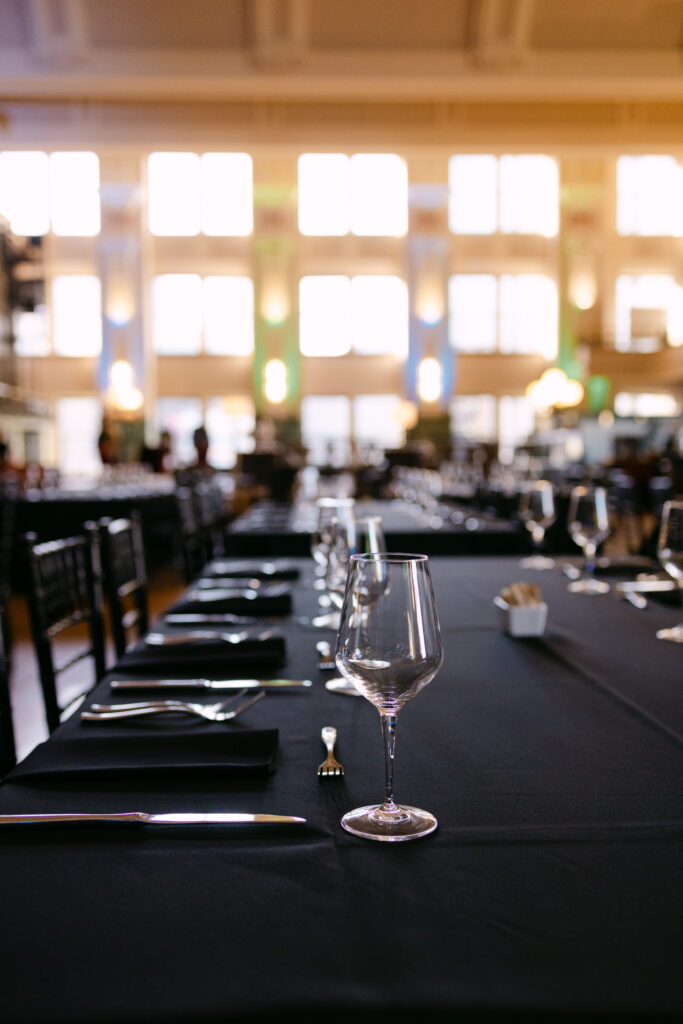 Black-draped dinner table with crystal wine glasses set for MPR corporate gala at the Minneapolis Grain Exchange — Mycah Bain Photography