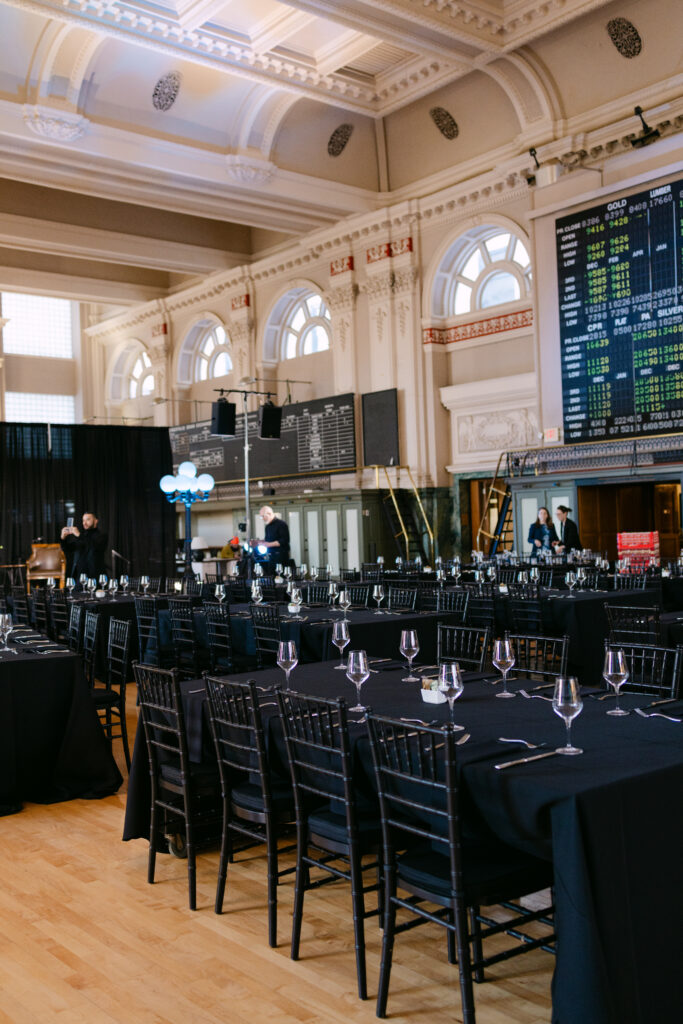 Wide shot of Minneapolis Grain Exchange trading floor set for MPR corporate event dinner with historic stock ticker board visible — Minneapolis corporate event photographer