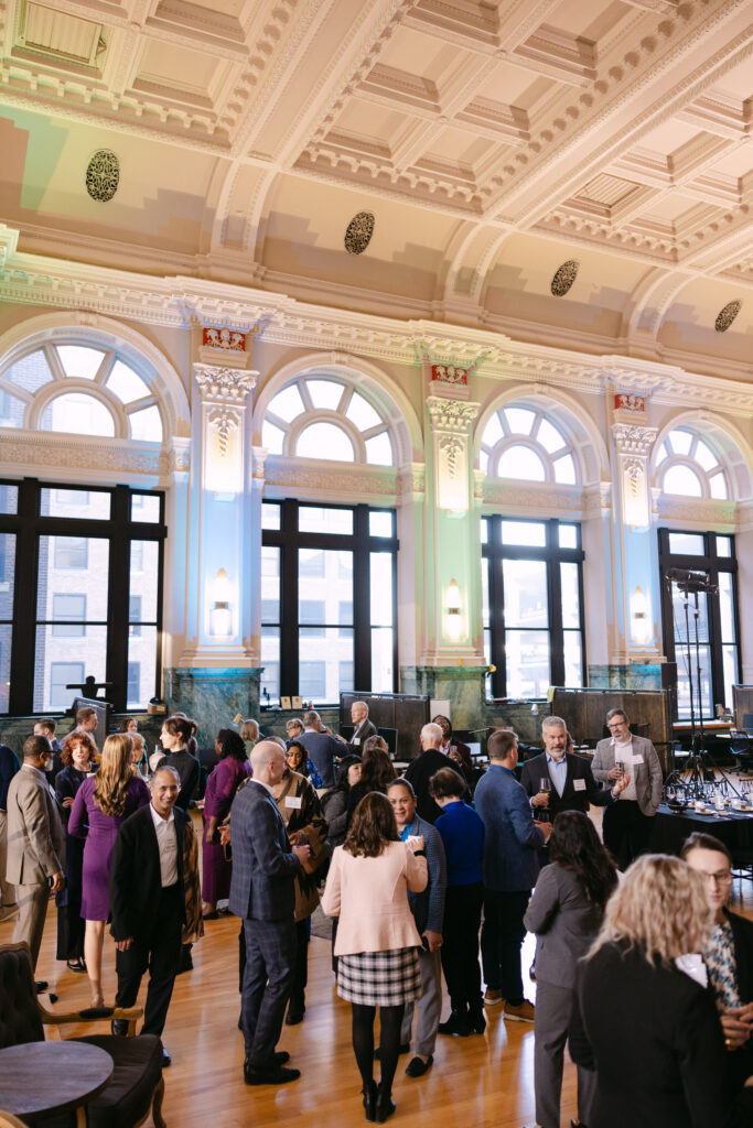 Aerial view of MPR corporate event guests networking in the grand hall of the Minneapolis Grain Exchange with ornate arched windows — Mycah Bain Photography