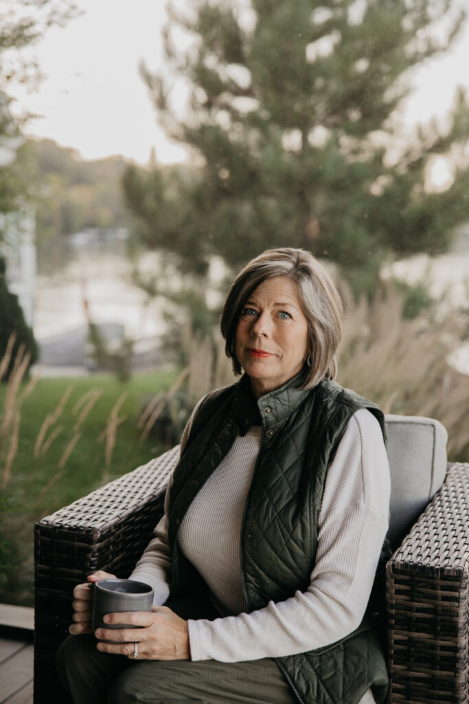 Dr. Melissa Polusny Minneapolis psychologist seated outdoors on lakeside deck during golden hour brand photography session by Mycah Bain Photography
