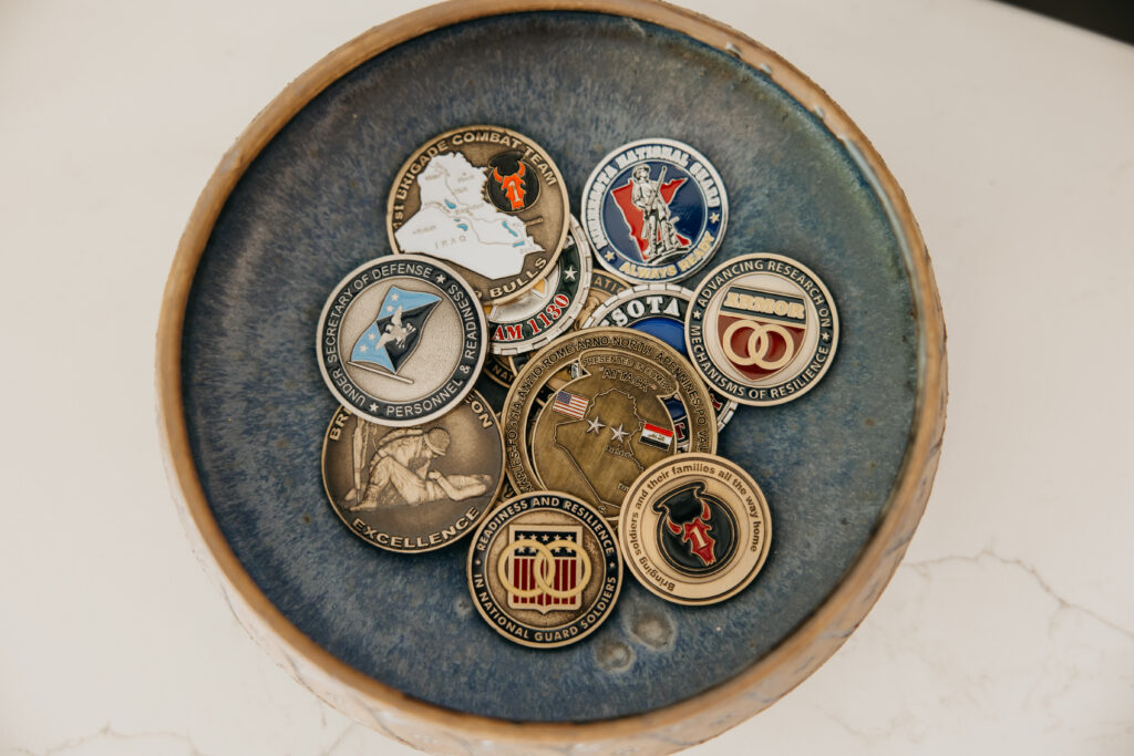 Military challenge coins in dish — B-roll detail representing veteran resilience work during brand photography psychologist Minneapolis session
