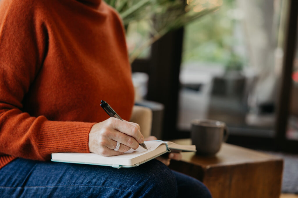 Close-up of Dr. Melissa Polusny writing in journal during brand photography psychologist Minneapolis session