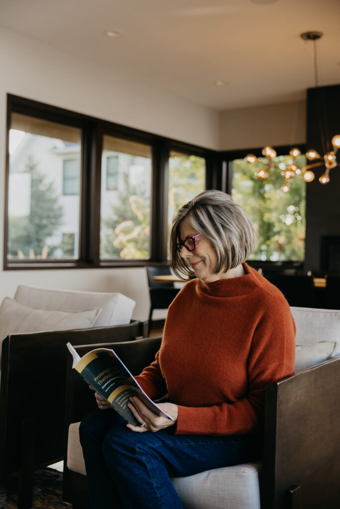 Dr. Melissa Polusny psychologist smiling while reading clinical book during brand photography session in Minneapolis by Mycah Bain Photography