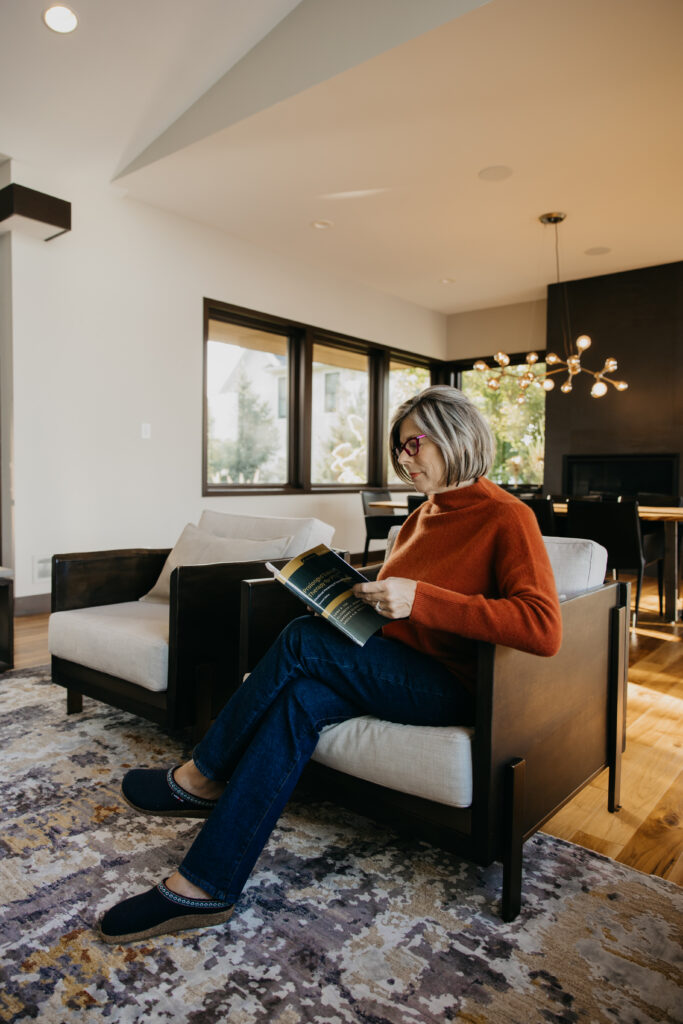 Dr. Melissa Polusny Minneapolis psychologist reading in armchair during brand photography session by Mycah Bain Photography