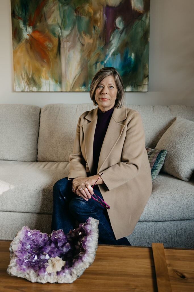Dr. Melissa Polusny psychologist seated on sofa next to amethyst crystal during brand photography psychologist Minneapolis session