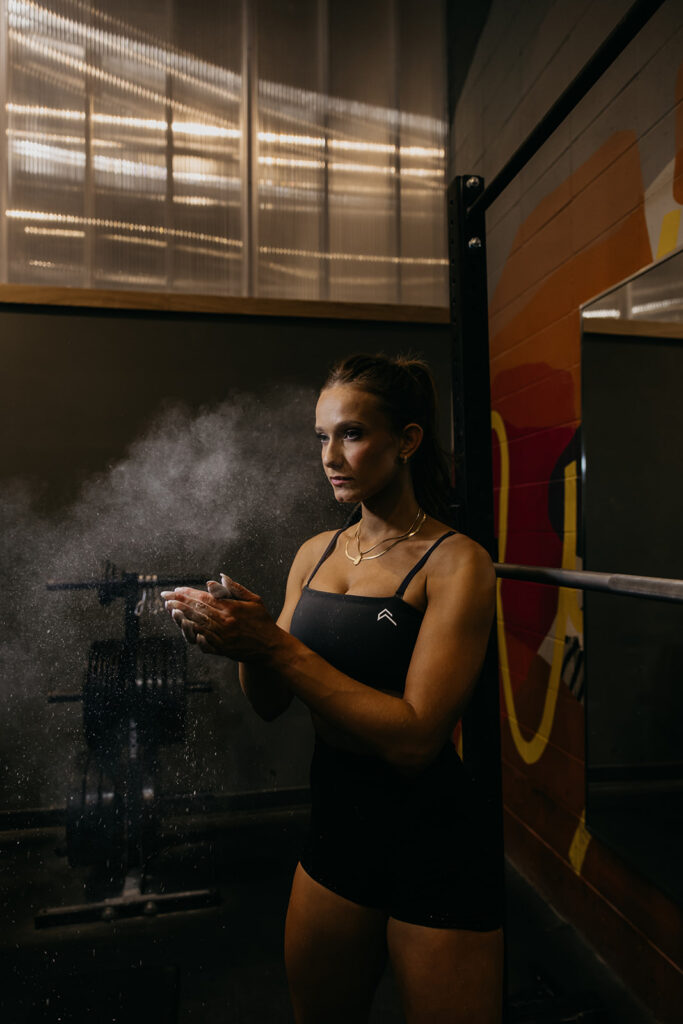 Lili Pfeifer of The Barbell Ballerina chalking hands in gym during fitness brand photography Minneapolis session by Mycah Bain Photography