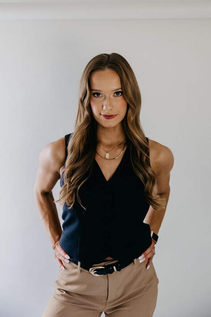 Lili Pfeifer of The Barbell Ballerina standing confidently in black sleeveless top and tan trousers during fitness entrepreneur brand photography Minneapolis session