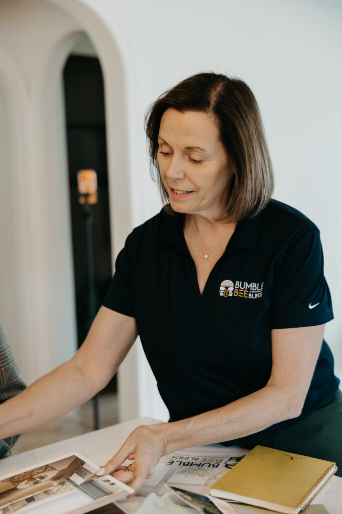 Bumble Bee Blinds team member reviewing a printed catalog at a table with sample books