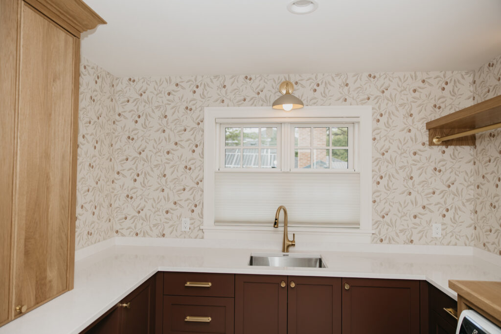 Finished kitchen with cellular shade installed above a brass faucet and farmhouse sink