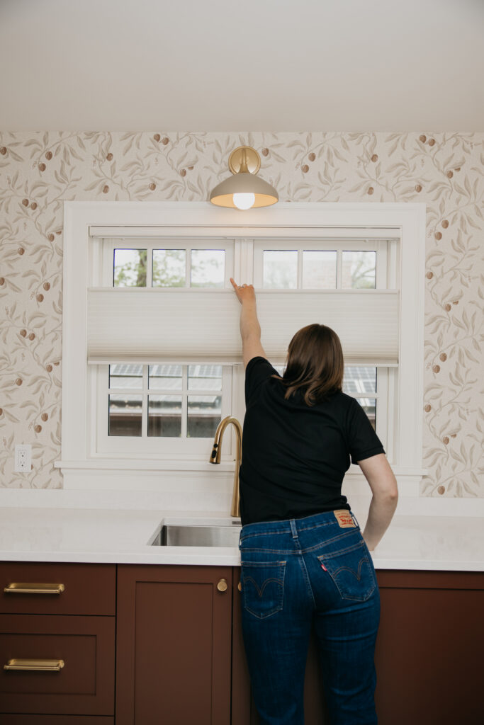 Bumble Bee Blinds team member adjusting a cellular shade above a kitchen sink