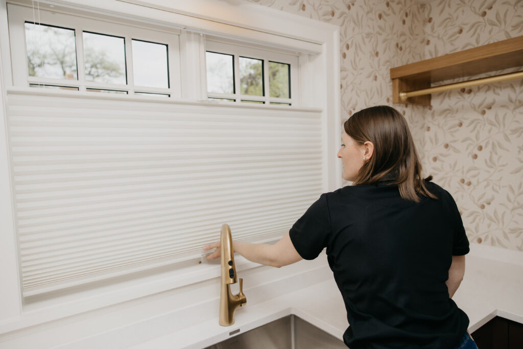 Bumble Bee Blinds team member testing a cellular shade above a kitchen sink