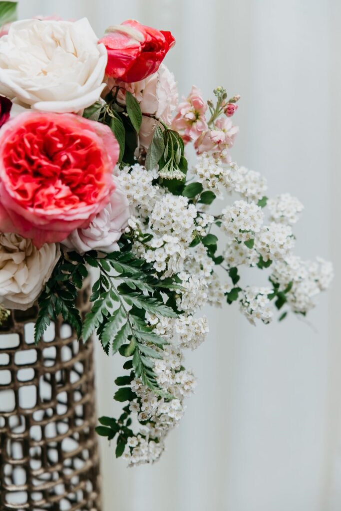Close-up of a pink coral and white floral arrangement in a gold vase against a white background during Haute House Studio brand session