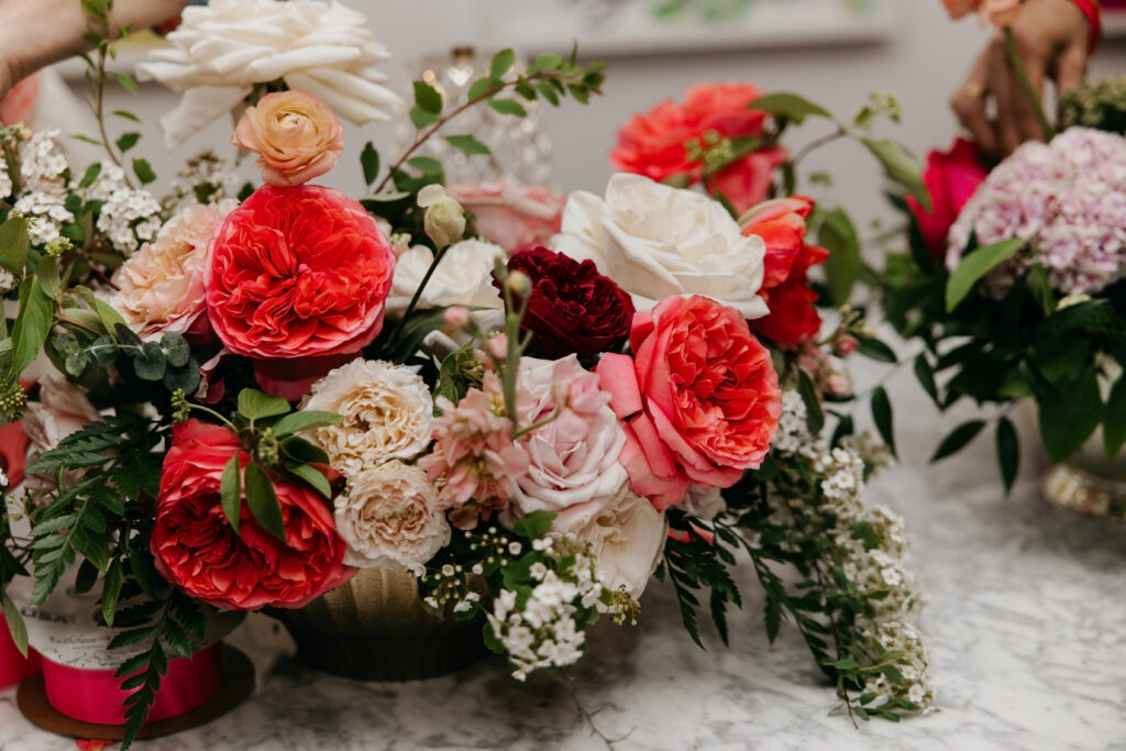 Lush floral centerpiece with red coral blush and cream garden roses ranunculus and cascading greenery on a marble surface during Haute House Studio brand photography session in Edina Minnesota by Mycah Bain Photography