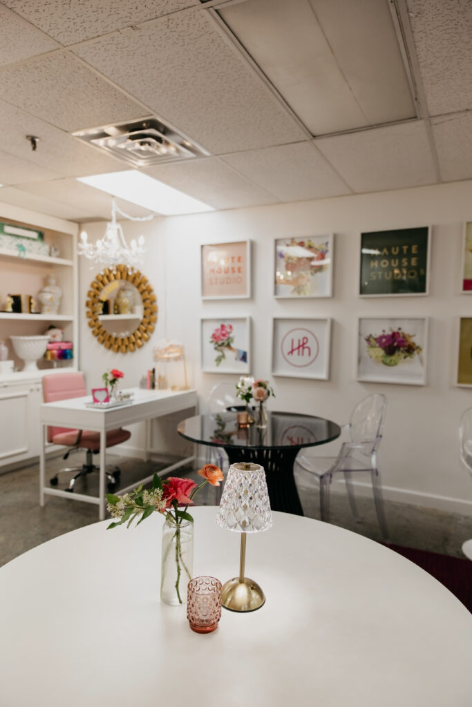 Wide shot of the Haute House Studio interior in Edina MN with white tables ghost chairs and styled floral accents throughout the space