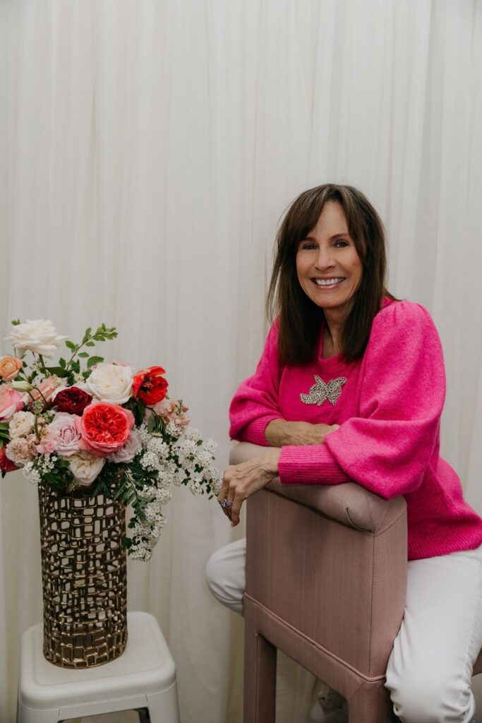 Haute House Studio team member in a hot pink sweater leaning on a gold vase with garden roses during brand photography session Edina MN