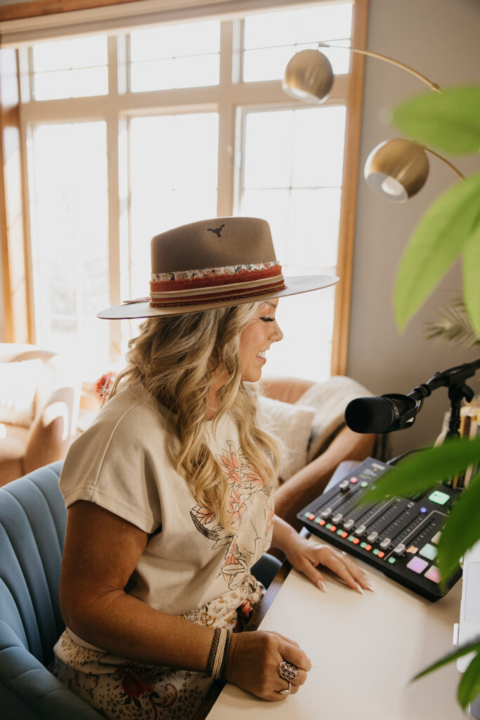 Women's mentor seated at podcast desk with microphone and mixing board during Minneapolis brand photography shoot
