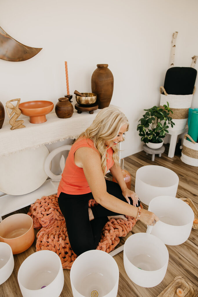 Women's wellness coach playing crystal singing bowls on the floor of her healing studio during Minneapolis brand shoot