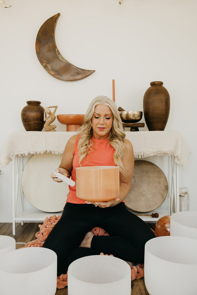 Close-up of women's energy healer holding a copper singing bowl in a sacred sound healing studio during brand shoot