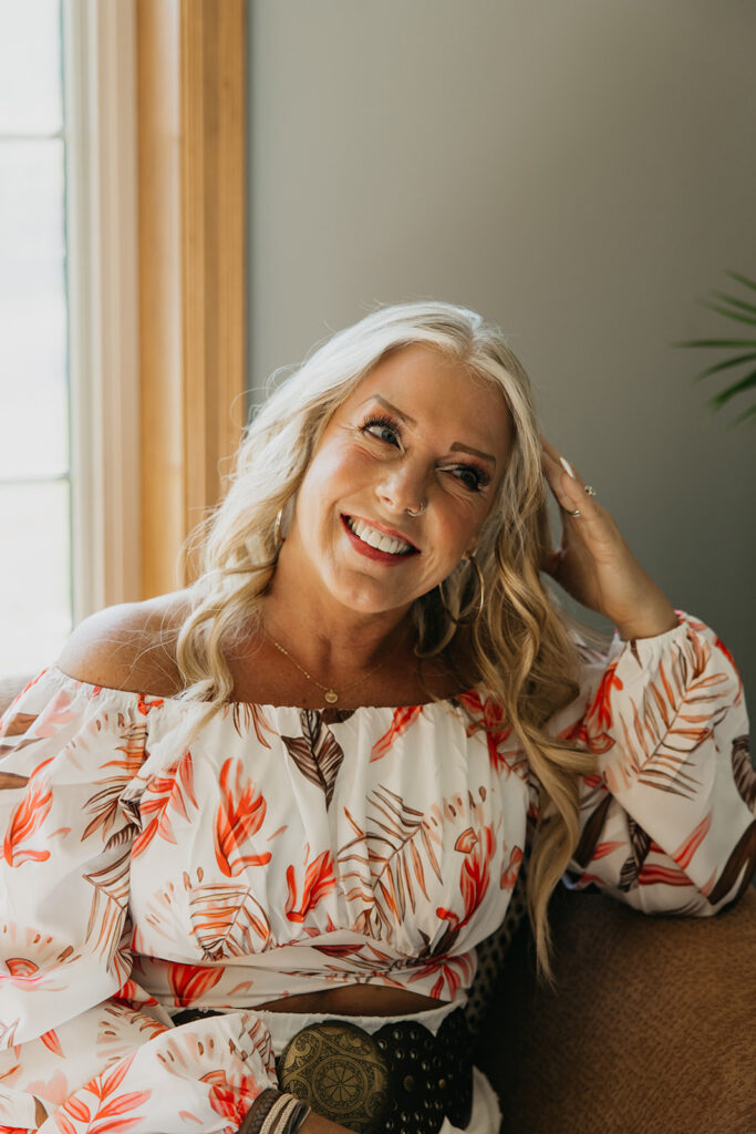 Women's mentor laughing in close-up portrait during brand photo shoot, wearing floral off-shoulder top