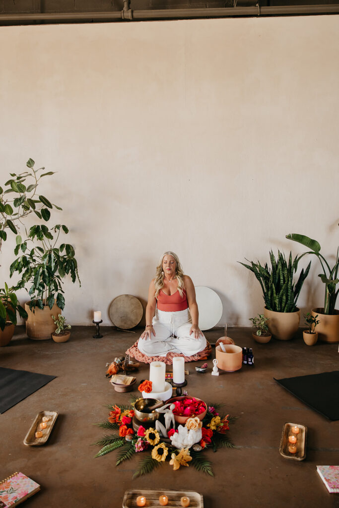Women's energy healer meditating in a circle of flowers and candles during Minneapolis brand shoot