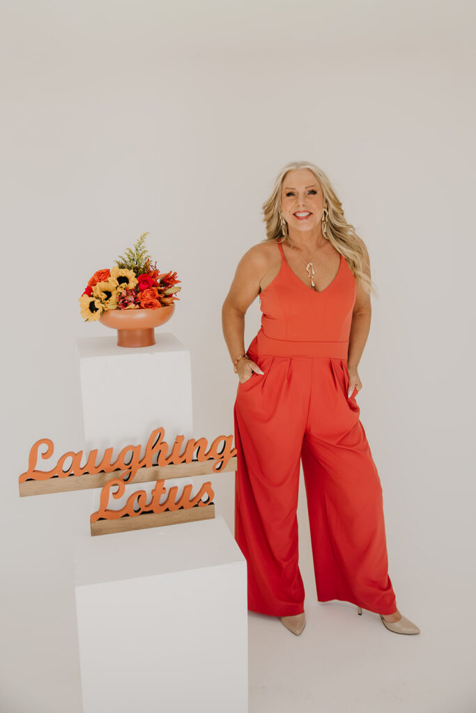Women's wellness coach standing beside Laughing Lotus branded sign with sunflowers during brand photography session in Minneapolis