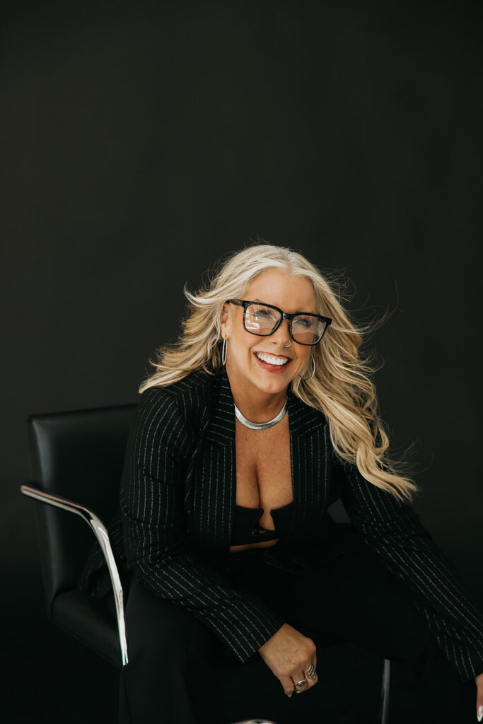 Women's wellness coach in black blazer and glasses posing during Minneapolis brand photography session