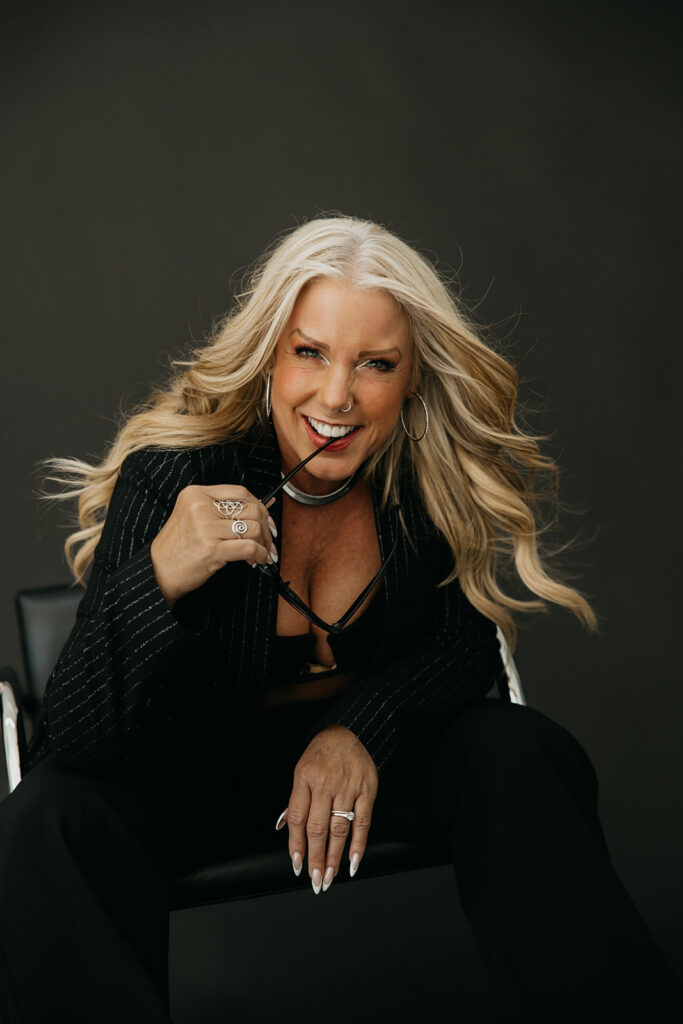 Women's wellness coach leaning toward the camera with wind-blown hair during bold brand photography session in Minneapolis